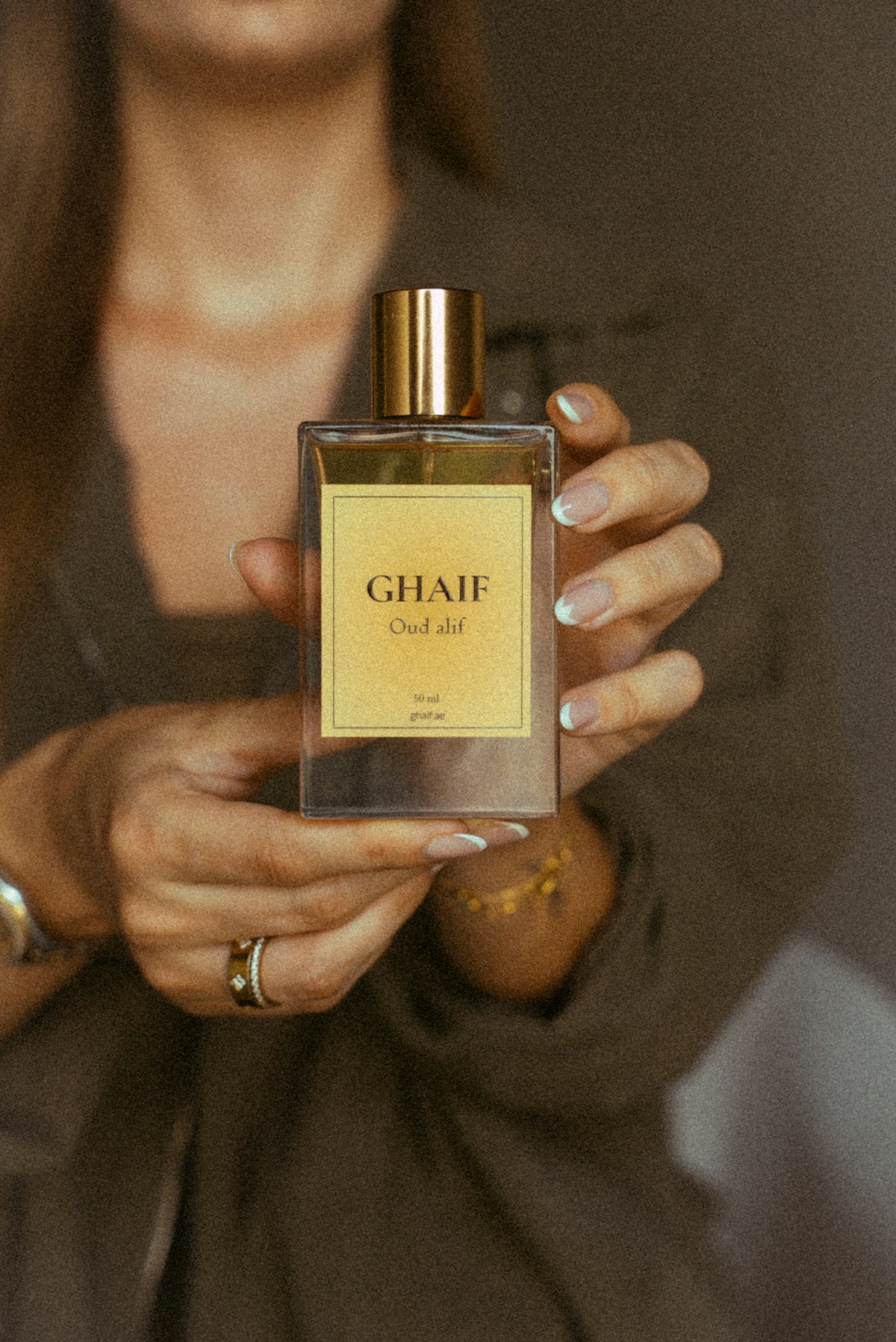 Hands holding ghaif oud alif perfume bottle