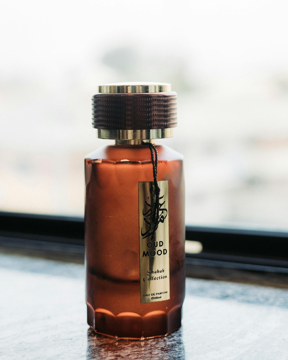 A bottle of oud mood perfume with a gold label