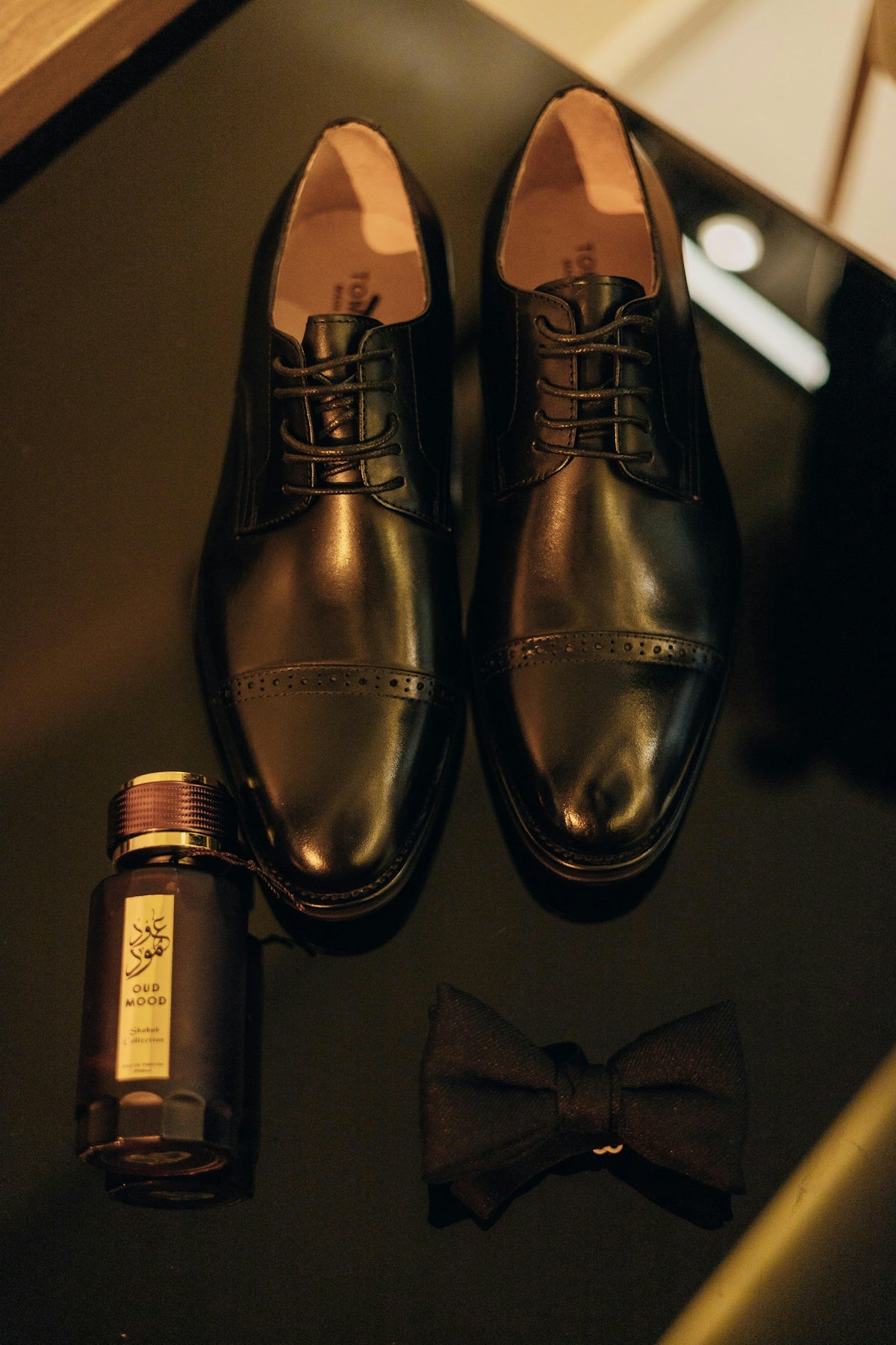 Men's black dress shoes, cologne, and bow tie